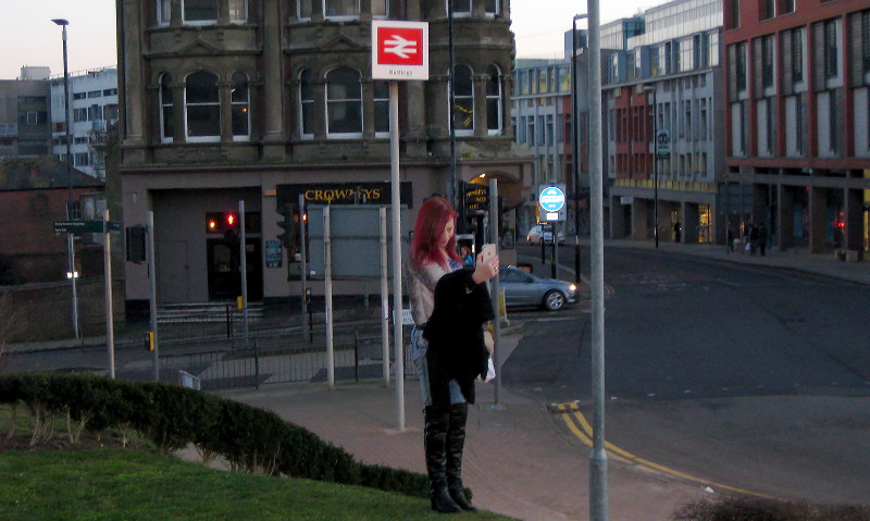 Sue by a Hastings
                      station sign